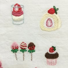 some embroidered items are sitting on a white surface and one is pink, the other is red