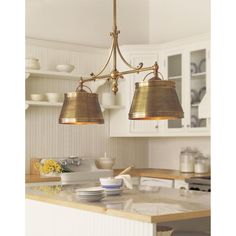 a kitchen with two lights hanging from the ceiling and plates on the counter in front of it