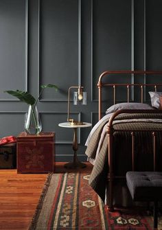 a bed room with a neatly made bed next to a rug and a lamp on a table