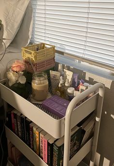 a table with books, jars and other items on it in front of a window