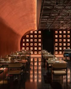 a dimly lit restaurant with tables and chairs in front of a large wooden paneled wall