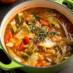 a green pot filled with vegetable soup on top of a table