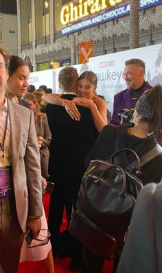 a group of people standing next to each other on a red carpet at an event