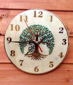 a clock with a tree painted on the face and numbers around it's sides