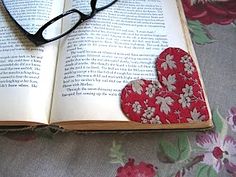 an open book with two hearts and glasses laying on top of it next to a pair of eyeglasses