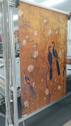 an orange wall with birds and flowers painted on it's side, next to a machine