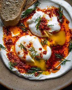 two eggs are on a plate with bread and seasoning sprinkled around them