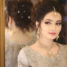 a woman is looking in the mirror with her hair pulled back and wearing an elaborate head piece