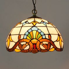 a stained glass light hanging from a ceiling fixture with an ornate design on the bottom