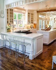 a large kitchen with white cabinets and an island in the middle of the room that has bar stools on it