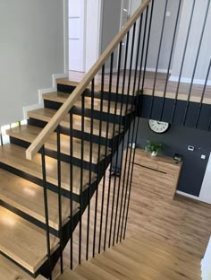 a wooden staircase with black handrails in a living room next to a white wall