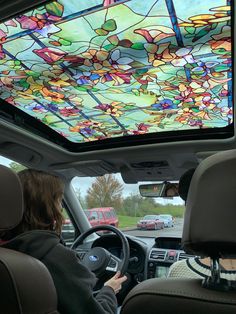 a woman driving a car with a colorful ceiling in the back seat and another vehicle behind her