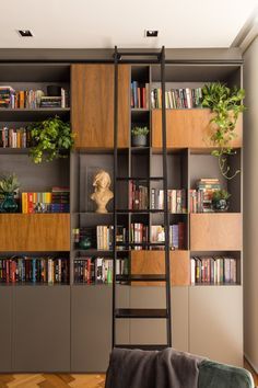 a living room with bookshelves and ladders to the ceiling, filled with plants