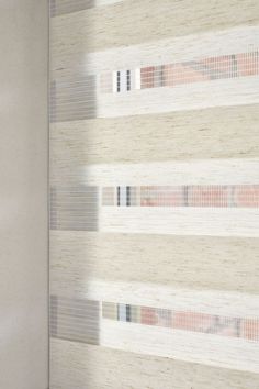 a white wall with vertical blinds on the side and behind it is a window that looks out onto an outside area