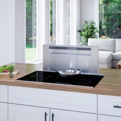 a stove top oven sitting on top of a wooden counter next to white cabinets and windows