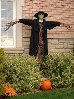 a scarecrow is standing in front of a house with his arms spread out to the side