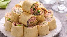 a plate full of rolls with meat and veggies on top, sitting on a table