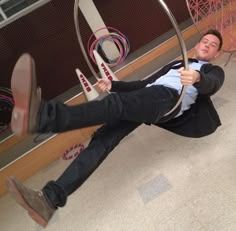 a man laying on top of a swing in an indoor area next to a building