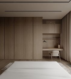 an empty bed sits in front of a wooden wall and desk with a large window