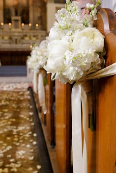 white flowers are tied to the pews of a church