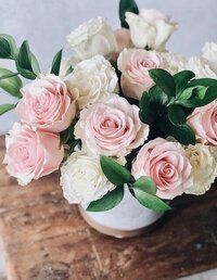 a white vase filled with pink and white flowers