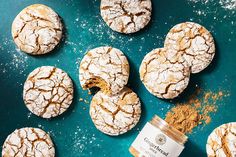 cookies and powdered sugar sit on a blue surface next to a jar of powder