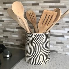 wooden utensils and spoons are in a zebra print cup on the kitchen counter