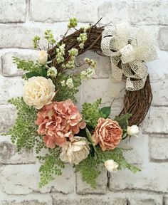 a wreath with flowers and greenery on a brick wall