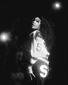 a black and white photo of a woman with long curly hair wearing a jacket that says s