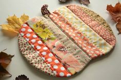 an orange and white patchwork pot holder next to autumn leaves