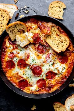 a pizza with pepperoni and cheese in a skillet next to some bread slices