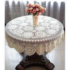 a vase with flowers is on top of a doily tablecloth that sits on a wooden stand