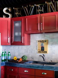 a kitchen with red cabinets and white tile backsplash