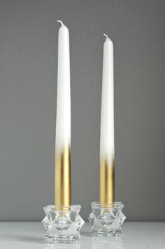 two gold and white candles sitting next to each other