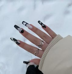 a woman's hand with black and white nail polish on it, holding two rings