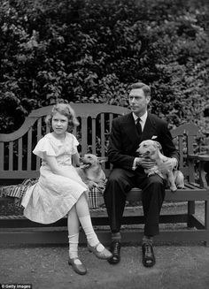 a man and woman sitting on a park bench with two puppies in their lap