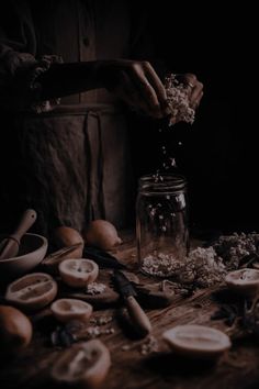 a person is sprinkling flowers in a jar on a table with other items