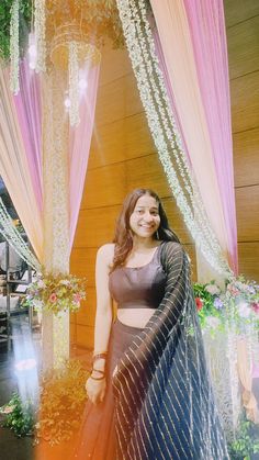 a woman standing in front of a decorated stage with pink drapes and white flowers