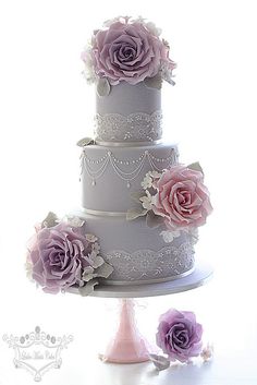 three tiered wedding cake with pink flowers on each layer and white lace trimmings