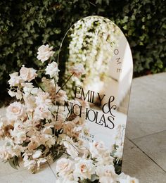 white flowers are placed in front of a mirrored sign that says, family & nicholas