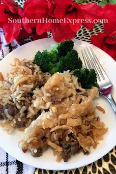 a white plate topped with rice and broccoli next to a knife and fork