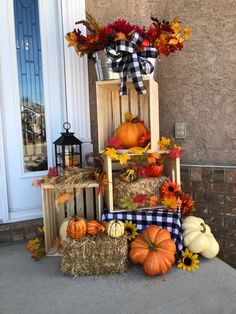 pumpkins, hay bales and sunflowers are arranged on the front porch