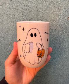 a hand holding a coffee cup with a ghost on it