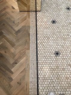 a person's feet standing on the floor in front of a tiled shower stall