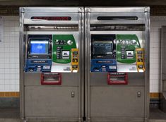 two atm machines sitting next to each other in a subway station with tile flooring