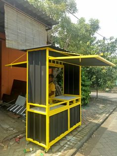 a yellow and black structure sitting on the side of a road next to a building