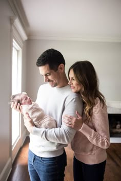 a man and woman holding a baby in their arms