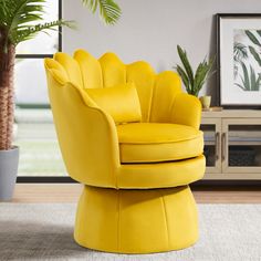 a yellow chair sitting on top of a rug next to a potted plant