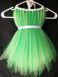 a green dress hanging on a hanger in front of a black background with white trim