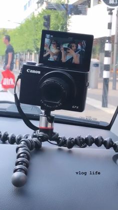 a camera sitting on top of a car dashboard next to a tripod with a person walking in the background